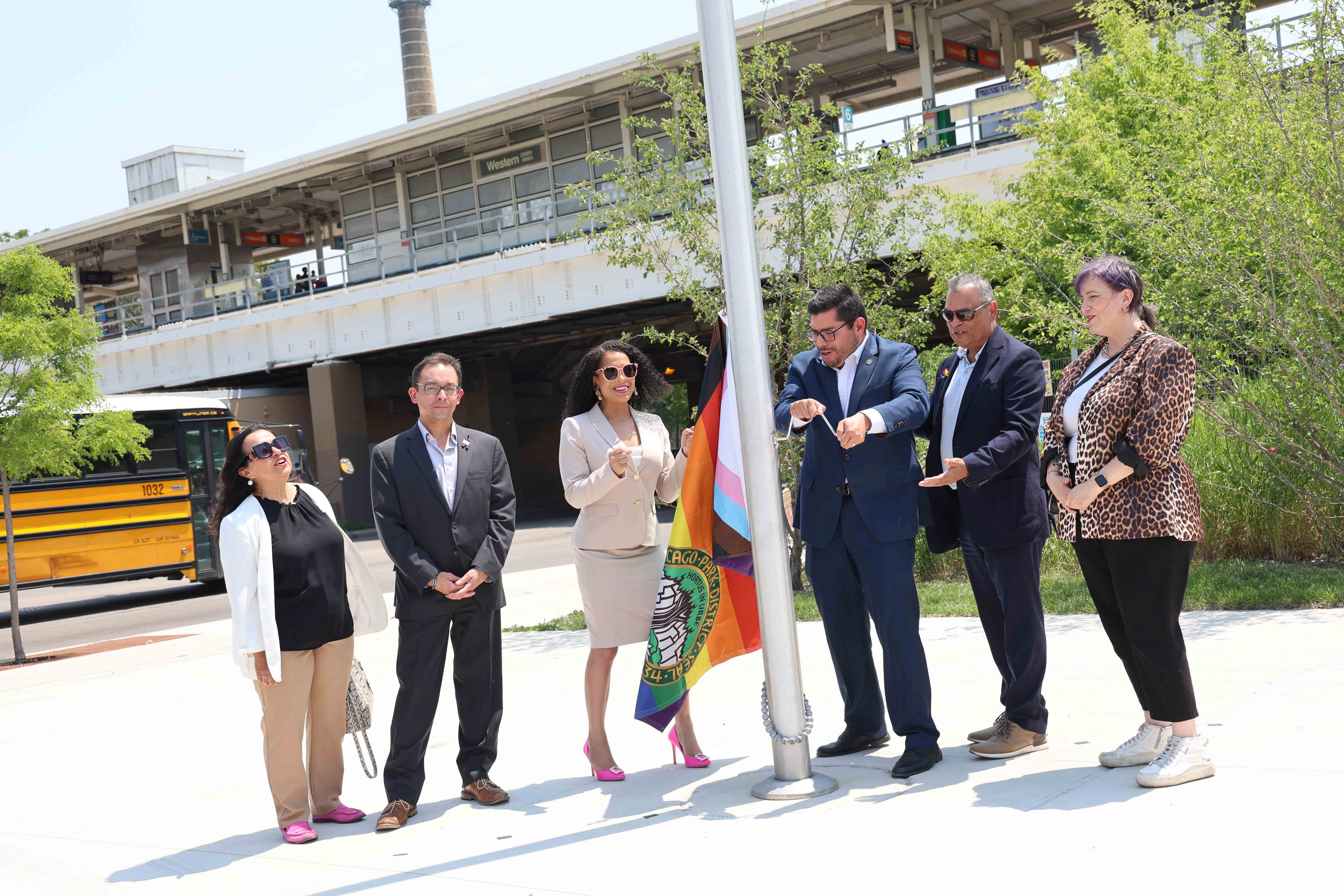 Group raises Progress Pride flag at a ceremony.
